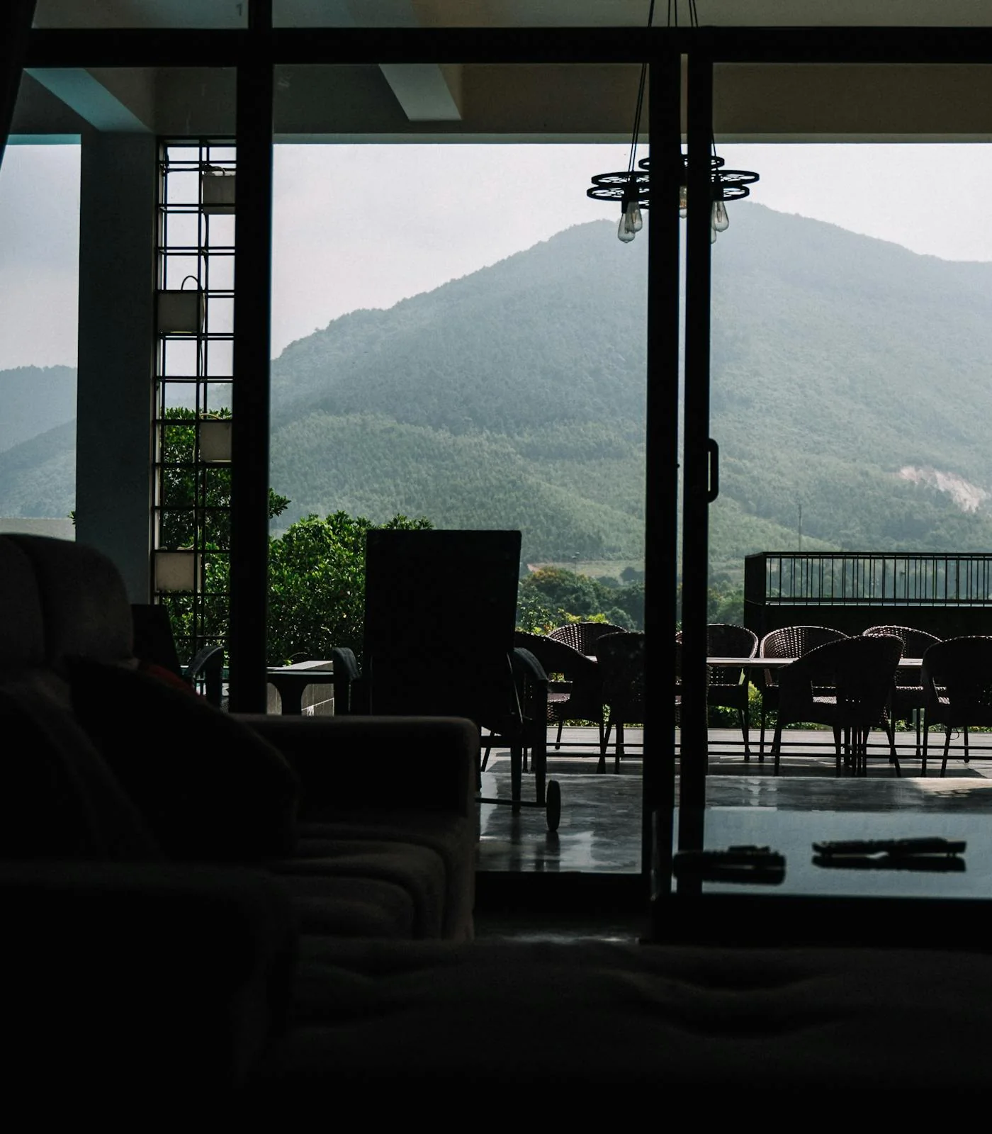Terrace view through glass doors toward green mountains